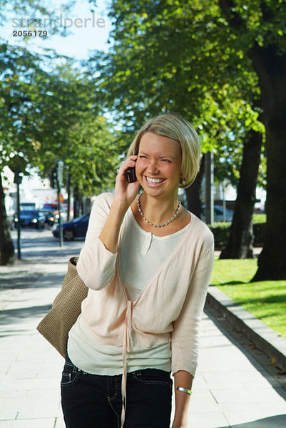 Junge Frau spricht auf ihrem Handy in der Innenstadt.