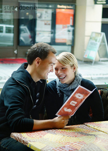Junges Paar in einem Restaurant im Freien mit Blick auf die Speisekarte