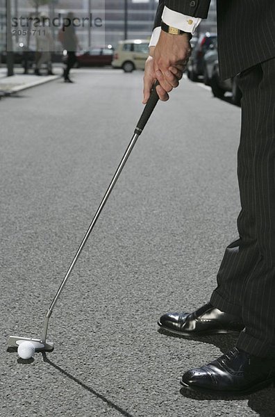 Ein Geschäftsmann spielt Golf auf der Straße