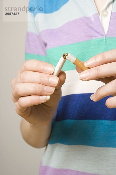 Eine Frau bricht eine Zigarette in zwei Stücke