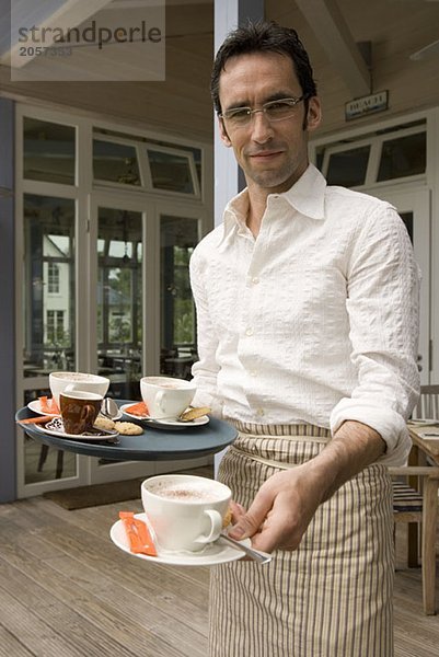 Ein Kellner mit Kaffeetassen auf seinem Tablett