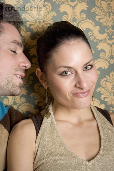 Ein Mann beugt sich vor um einer Frau etwas in das Ohr zu flüstern