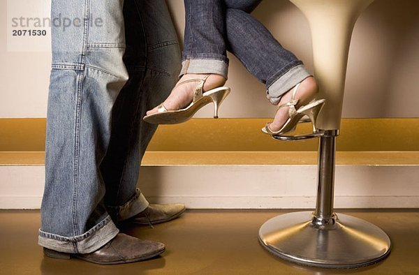 Füße und Beine eines jungen Paares zusammen an der Bar