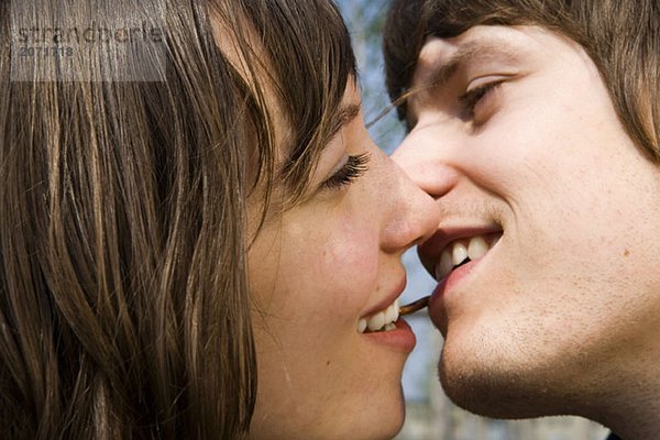 Junges Paar knabbert eine Brezel und küsst sich