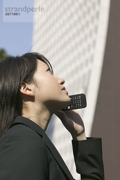 Eine junge Geschäftsfrau mit einem Mobiltelefon neben einem Wolkenkratzer