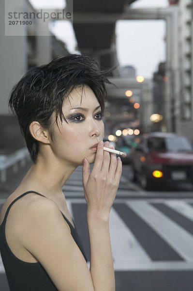 Porträt einer rauchenden jungen Frau auf einer Straße  Tokio  Japan