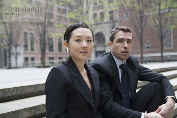 Ein Geschäftsmann und eine Geschäftsfrau sitzen auf einer Treppe