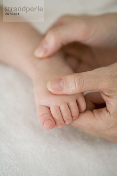 Eine Mutter berührt den Fuß eines Babys
