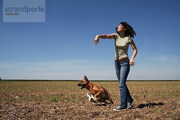 Junge Frau mit Hund im Feld spielen