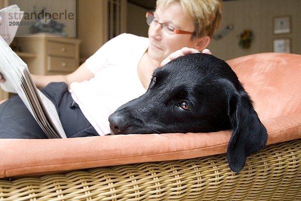 Frau lesen Zeitung mit Hund auf couch