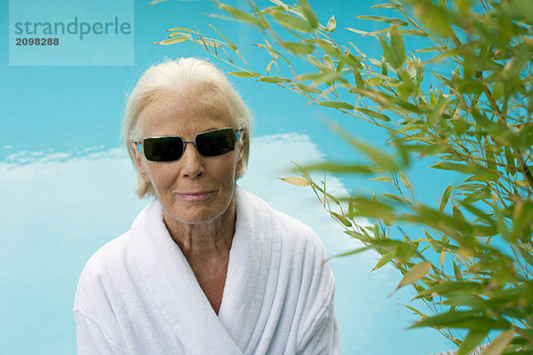 Germany  senior woman at pool  wearing sun glasses