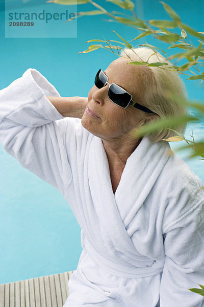 Germany  senior woman at pool  wearing sun glasses