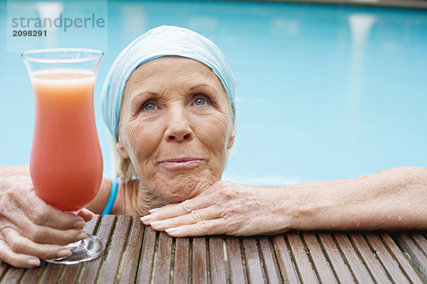 Deutschland  Seniorin beim Cocktail am Pool