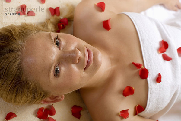 Germany  woman lying on back  petals on chest