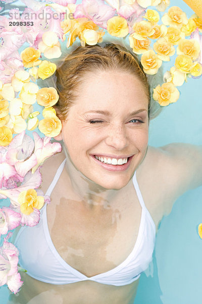 Deutschland  junge Frau im Pool mit Blumen
