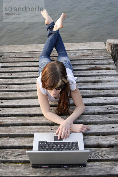 Italien  Gardasee  Junge Frau (20-25) mit Laptop am Dock  Nahaufnahme