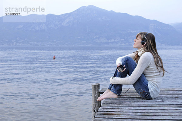 Italien  Gardasee  Junge Frau (20-25) am Steg mit eigener Stereoanlage