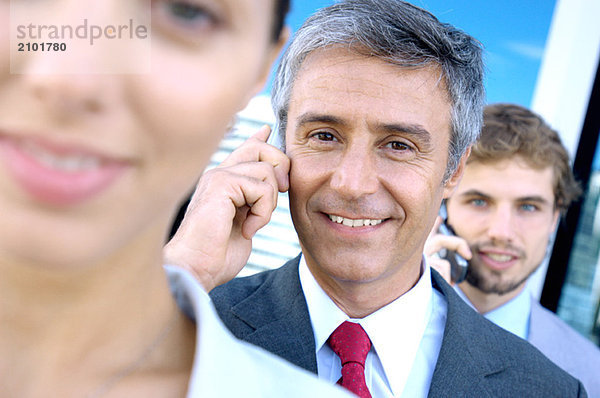 Geschäftsleute  die Mobiltelefone benutzen  lächelnd