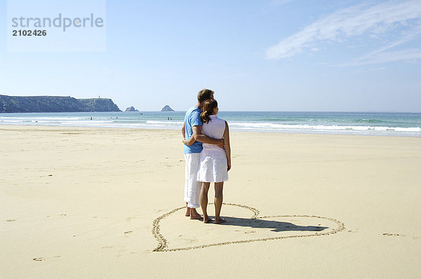 Rückansicht des Paar steht in Heartshape am Strand