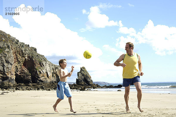 Vater Fussballspielen mit seinem Sohn am Strand