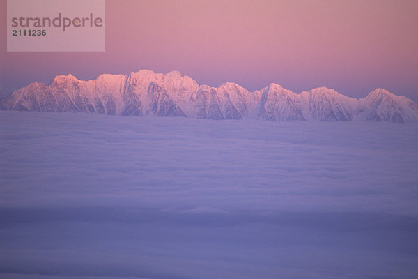 Mountain ridge called the Steeples in evening light with cloud inversion  East Kootenays  B.C.