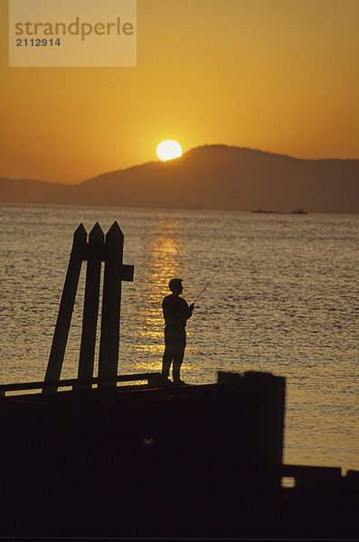 Teenager fishing off dock at sunset  San Juan Islands  Washington