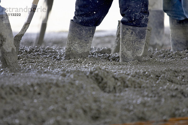 'Detail of workers wearing rubber boots in cement