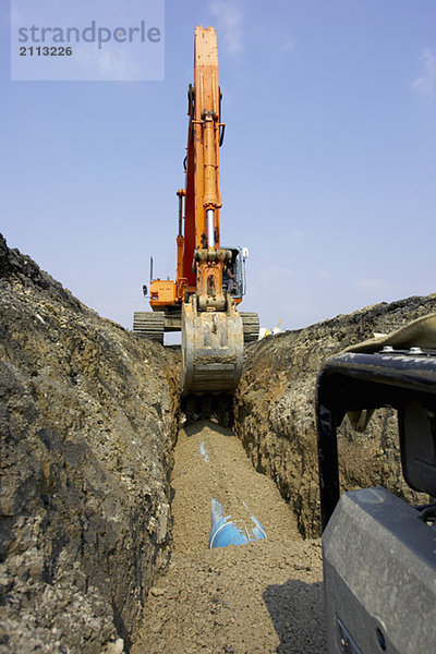 'Excavator filling in section of drainage pipe with dirt