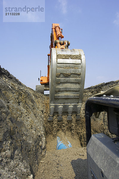 'Excavator filling in section of drainage pipe with dirt