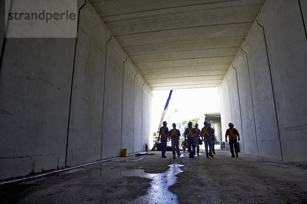 'Workers walking down a concrete tunnel