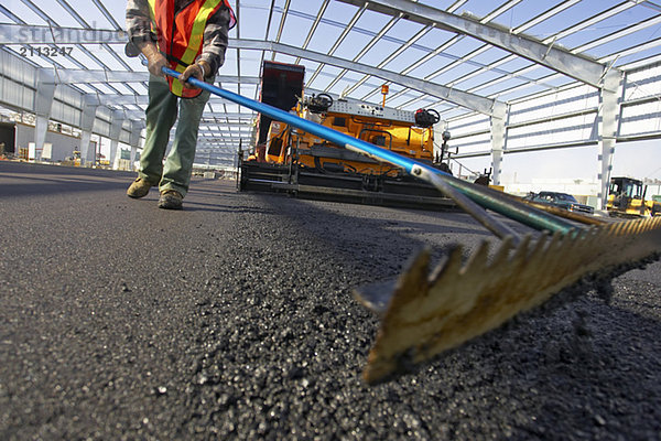 'Worker leveling asphalt with a rake