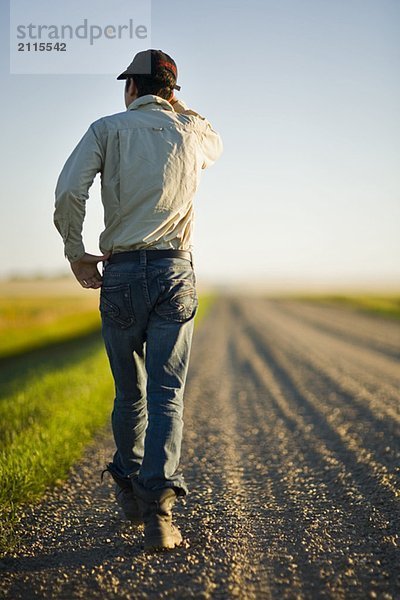 Man walking along gravelled road in rural Saskatchewan  Canada