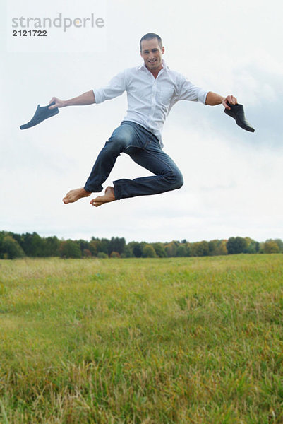 Barfüßiger Mann  der auf ein Feld springt.