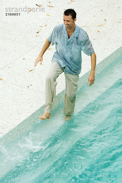 Mann beim Plantschen im Pool  voll bekleidet  hohe Blickwinkel