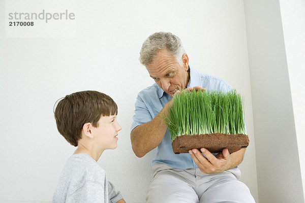 Mann mit falschem Gras und Gespräch mit Enkel  beide lächelnd