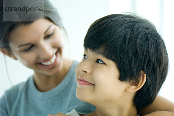 Junge schaut Schwester über die Schulter  beide lächelnd