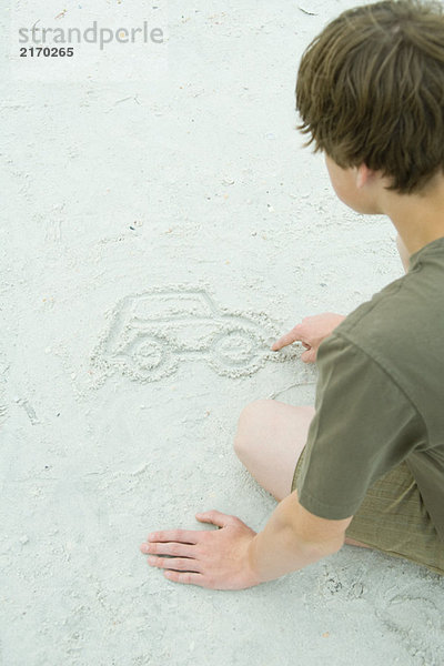 Jugendlicher Junge zeichnet Auto in Sand