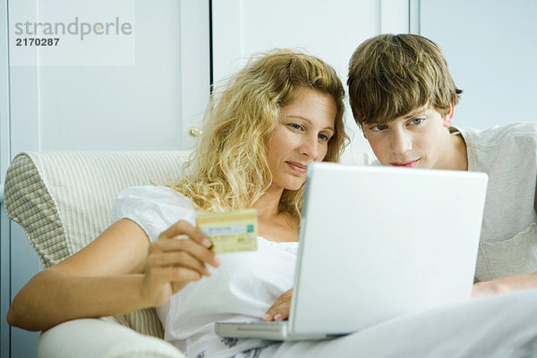 Frau und jugendlicher Sohn beim Online-Kreditkartenkauf
