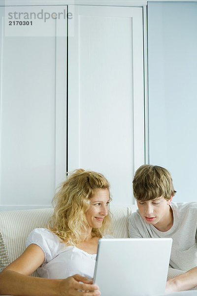 Frau und Teenager-Sohn mit Laptop zusammen