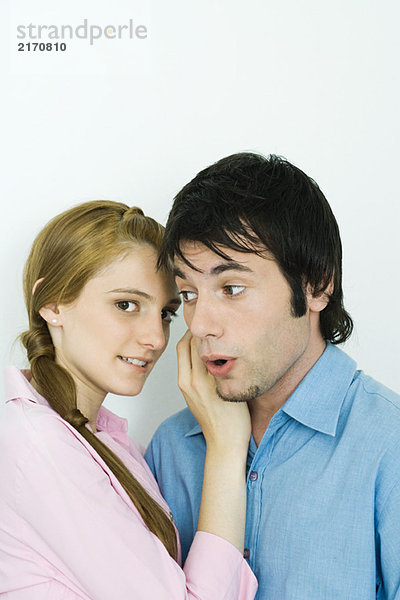 Junges Paar zusammen  Frau schaut über die Schulter zur Kamera  Mann schaut mit offenem Mund weg