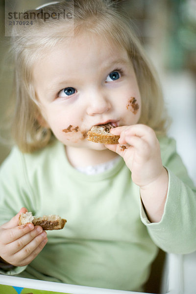 Blondes Kleinkind Mädchen beim Brotessen mit Schokolade