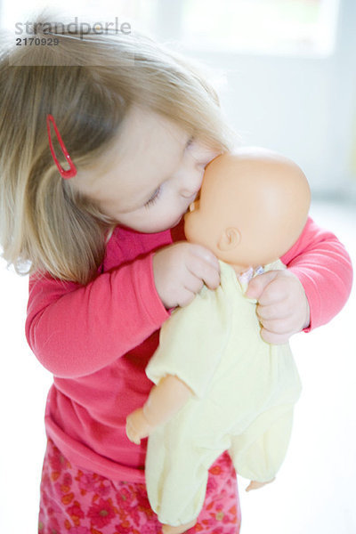 Blondes Kleinkind Mädchen küsst Babypuppe