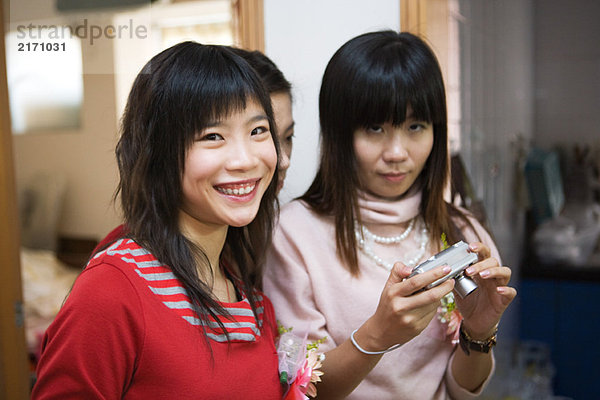 Drei junge Frauen in Korsagen  eine hält eine Digitalkamera.