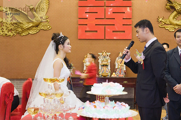 Braut und Bräutigam stehen von Angesicht zu Angesicht  schauen einander an  Bräutigam spricht ins Mikrofon