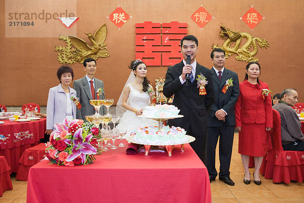Bräutigam steht vor Braut und Eltern  spricht ins Mikrofon