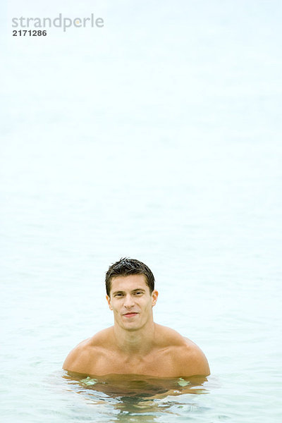 Muskulöse Männerbrust tief im Wasser  lächelnd vor der Kamera  Frontansicht
