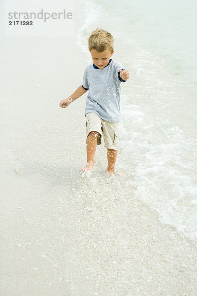Kleiner Junge beim Surfen am Strand  volle Länge