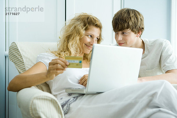 Frau und Teenager-Sohn mit Laptop  Online-Einkauf mit Kreditkarte