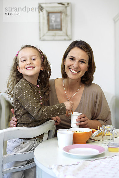 Portrait von Mädchen und ihre Mutter lächelnd am Frühstückstisch