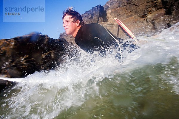 Mann auf dem Surfbrett im Spritzwasser.